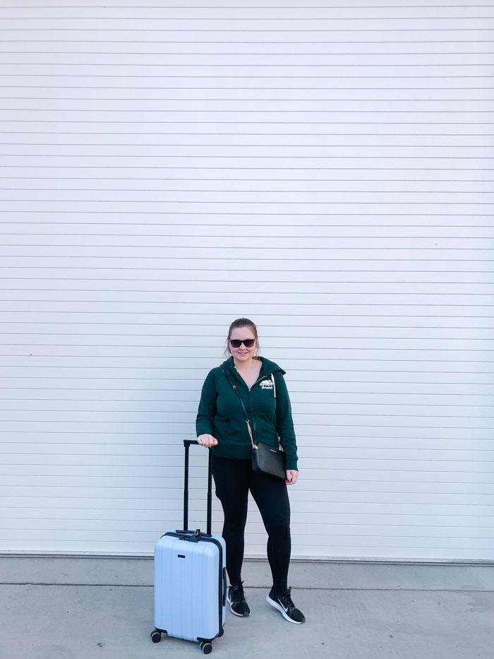 Girl with blue carry on luggage against white background