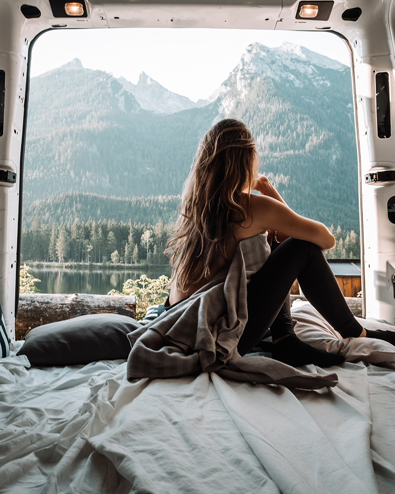 A woman looking at the view of mountains from the back of a van