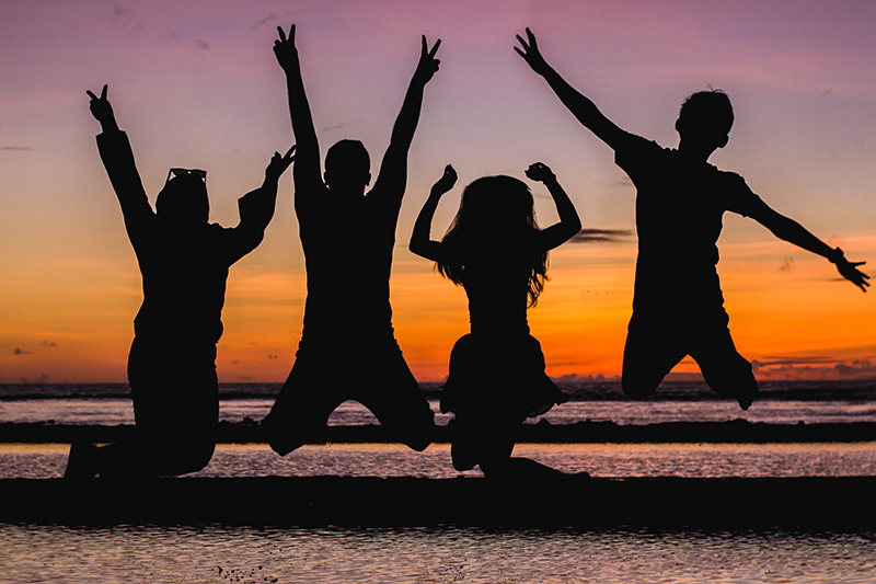 a group of friends jumping in the sunset