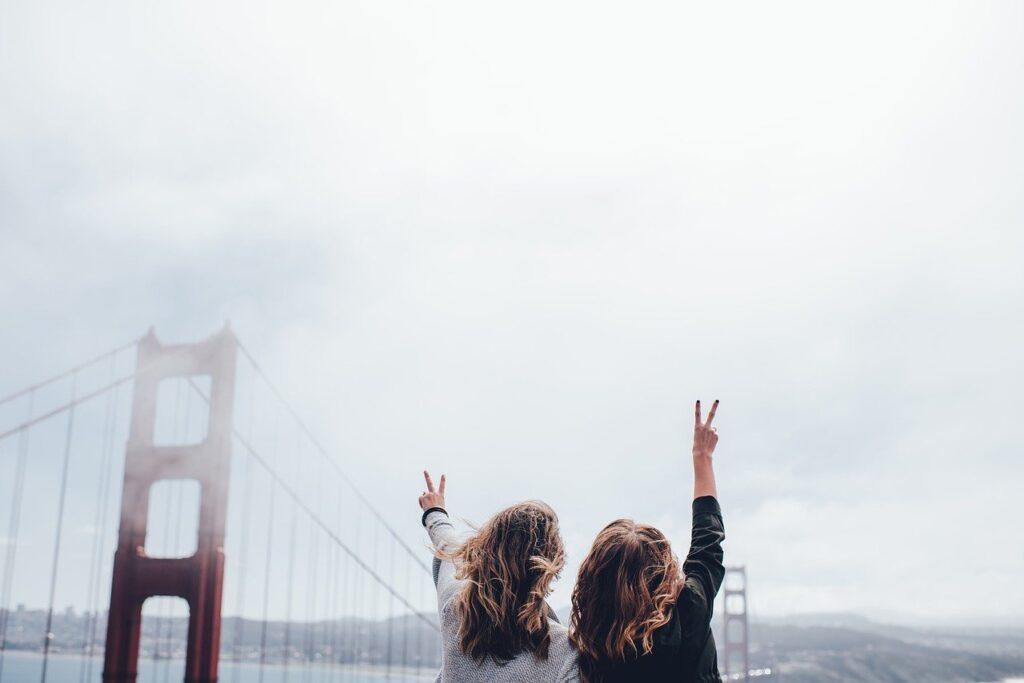 Two women giving a peace sign at the Golden Gate Bridge. San Francisco to Seattle Road Trip